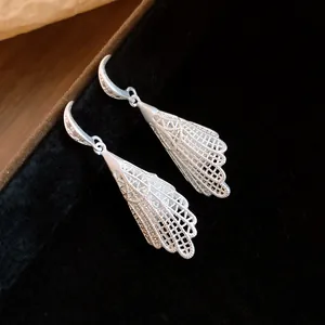 Detailed macro shot of the delicate silver hollow lace pattern on exquisite dangle earrings
