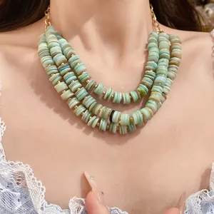 Close-up detail of three-layer green shell beaded necklace featuring gold spacer beads