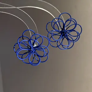 Detailed close-up of blue wire-wound flower stud earrings with a unique matte lacquer finish