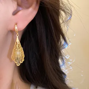 Detail shot of elegant hollow lace gold earrings with zircon and pearl pendant accents
