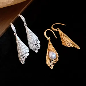 Detailed view of hollow lace earrings with pearls in gold and silver finishes