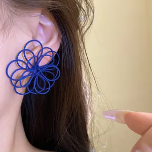 Detailed macro shot of an artistic blue wire-wrapped flower stud earring worn on an ear