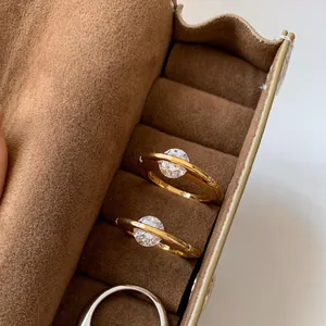 Nahaufnahme goldener Ringe mit rotierendem, glänzendem Zirkonia in einem Wildleder-Etui