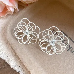 Macro view of white wire-wrapped hollow flower stud earrings featuring a unique design