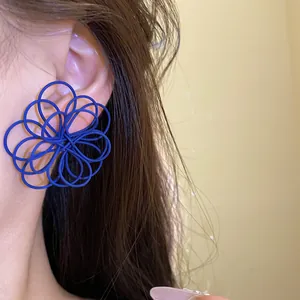 Detailed macro view of a unique blue wire-wound flower earring on a model's ear