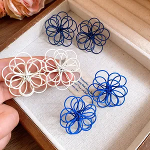 Detail showing unique hollow flower earrings with intricate painted wire wrap design.