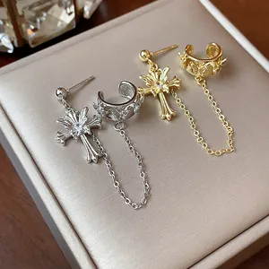 Detailed view of silver and gold gothic cross earrings with butterfly ear cuffs and chains.