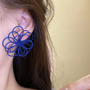 Detailed macro view showing the blue spray-painted intertwined flower wire stud earrings.