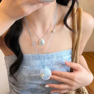 Bohemian vacation style blue cord layered necklace with sea shell and conch pendants for beach