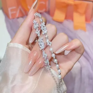 Sparkling marquise zircon and pearl bracelet held by a hand with manicured nails