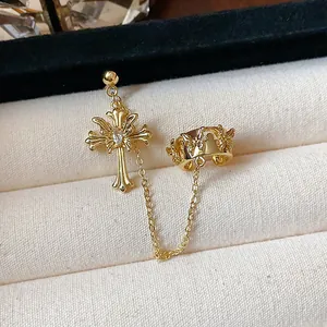 Detailed close-up of a 18k gold plated cross and butterfly ear cuff with chain connection.
