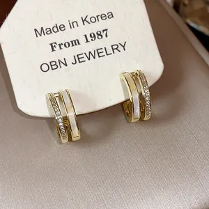 Detailed view of 14K gold plated C-shaped hoop earrings with mother of pearl and zircon.