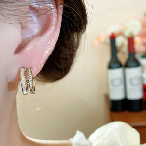 Detail view of 14k gold-plated C-shaped earrings with mother of pearl and zirconia