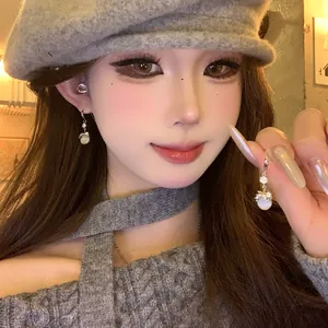 Detailed close-up of elegant resin drop earrings with rhinestones on an Asian model