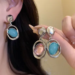 Close-up detail of retro silver needle earrings with blue and pink acrylic pendants