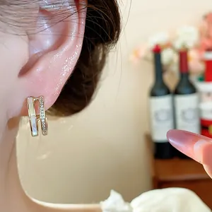 Close-up detail of 14k gold plated double-layer C-shape earrings with pearl inlay