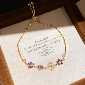 Detail view of a luxury gold zircon bracelet featuring purple floral charms in a box
