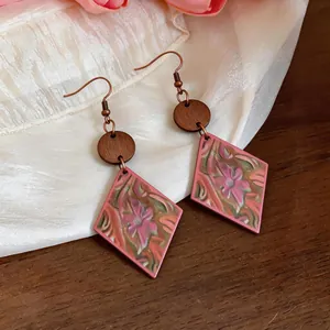 Close-up of bohemian pink diamond-shaped earrings with ethnic floral patterns and wood accents