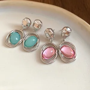 Detailed view of retro-style oval acrylic drop earrings in turquoise and pink colors.
