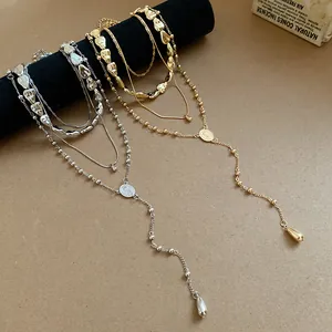 Macro view of layered necklace set featuring irregular beads and teardrop pendants in gold and silver