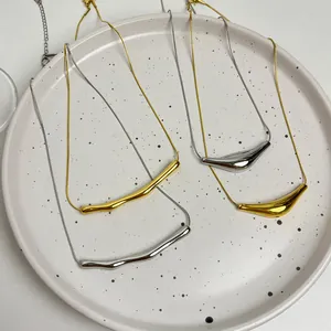 Detail view of minimalist gold and silver stainless steel smile pendant necklaces on a tray