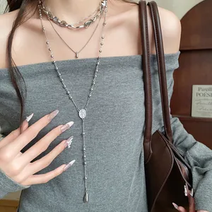 Close-up of layered irregular water drop pendant necklaces on a model wearing grey.