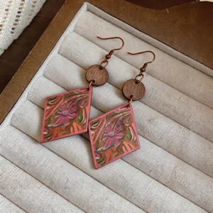 Close-up of ethnic pink diamond earrings with vintage floral patterns and wood accents.