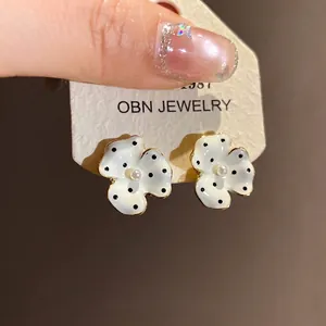 Elegant white flower stud earrings with black polka dots and a central pearl detail.