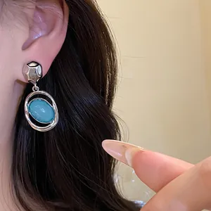 Retro silver-toned oval blue acrylic drop earrings on model detail view shot