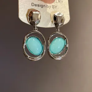 Close-up of vintage silver needle earrings with light blue oval acrylic pendants