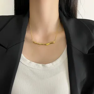 Detailed view of a gold curved bar necklace worn with a professional blazer outfit