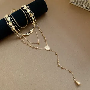 Close-up detail of a layered gold necklace set featuring irregular teardrop charms.