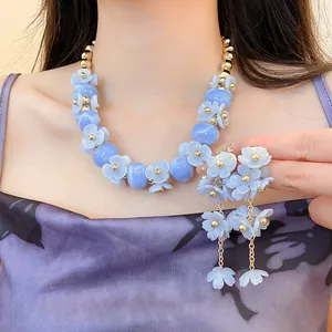 Vue détaillée de l'ensemble collier et boucles d'oreilles fleuris bleu clair sur modèle