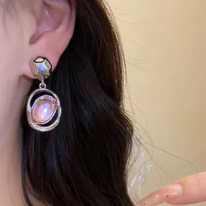 Detailed view of vintage silver needle earrings with a pink oval acrylic pendant on ear