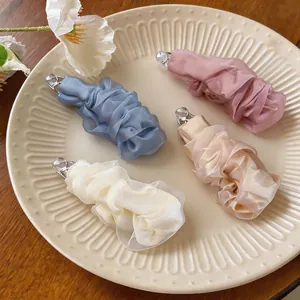 Dettaglio di fermagli per capelli in chiffon a pieghe in quattro colori pastello
