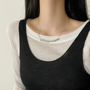 Close-up of a minimalist stainless steel smile pendant necklace on a model's neck