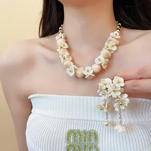 Gros plan d'un ensemble collier et boucles d'oreilles fleurs blanches sur un mannequin.