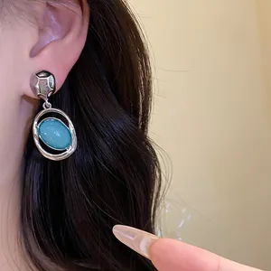 Detailed close-up view of vintage style blue acrylic oval pendant earring worn on ear