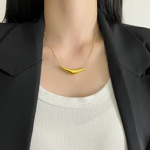 Detailed shot of a minimalist gold smile pendant necklace on a model wearing a blazer.