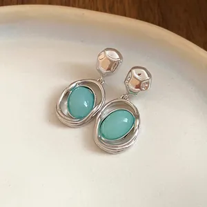 Close-up of retro silver needle earrings with oval sea-foam green acrylic stones