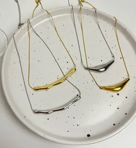 Macro view of four minimalist curved pendant necklaces in gold and silver finishes.