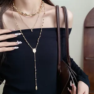 Detailed close-up view of a gold irregular teardrop pendant necklace set worn by a model