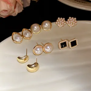 Detail view of vintage pearl and gold earring set on a white textured plate.