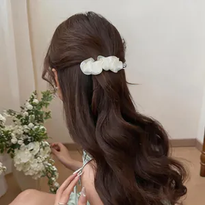 Dettaglio di un'elegante molletta per capelli in chiffon bianco su lunghi capelli mossi
