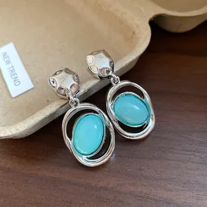 Macro view of vintage silver earrings with teal oval acrylic pendants on wood background