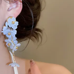Gros plan détaillé de boucles d'oreilles à fleurs bleu clair portées par un modèle
