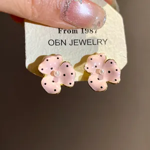 Macro view of pink flower stud earrings with elegant black polka dots and pearl center