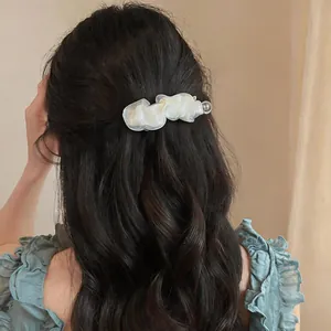 Elegante fermaglio per capelli in chiffon bianco su capelli scuri ondulati per un look chic