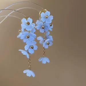 Gros plan de boucles d'oreilles à fleurs bleues avec détails de chaînes dorées élégantes