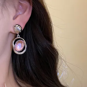 Detailed shot of retro acrylic oval pendant earrings elegantly worn on a woman's ear.
